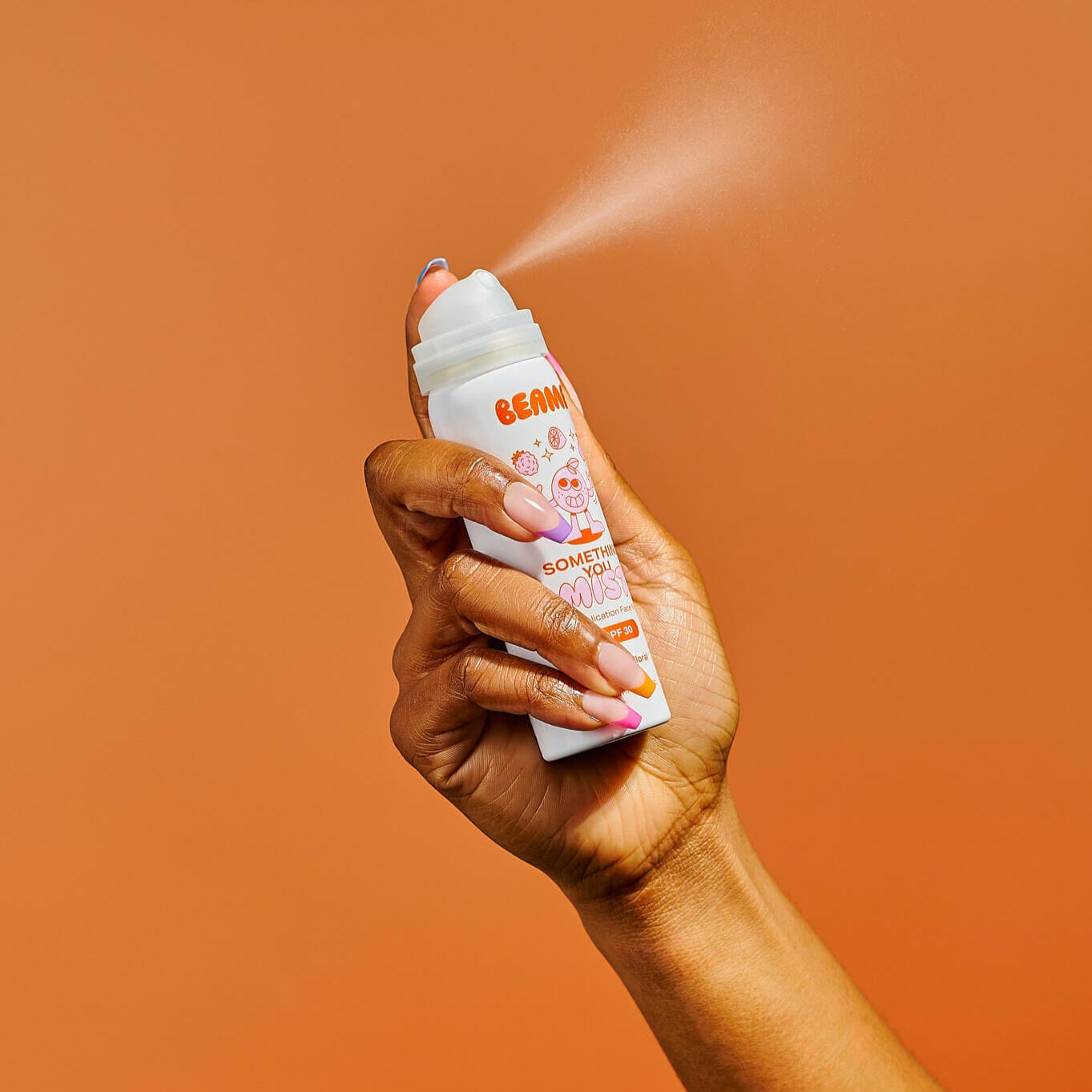 Hand holding a BEAME sunscreen bottle against an orange background