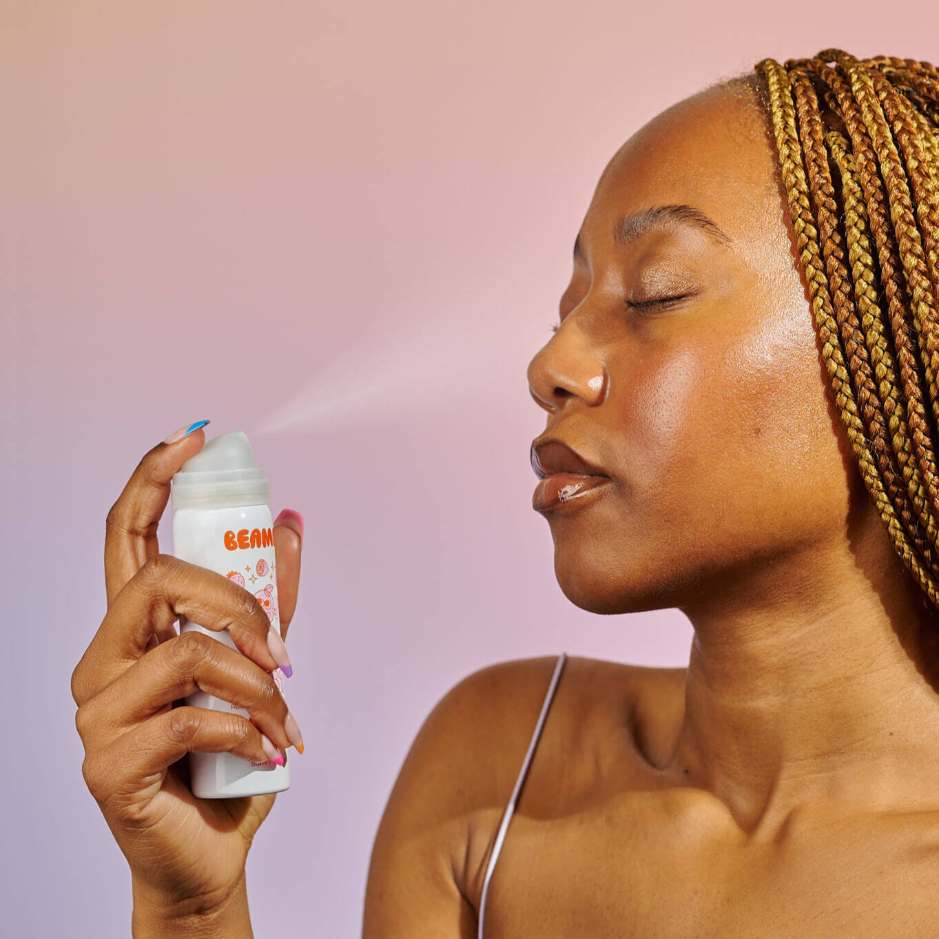 Woman applying a product to her face with a spray bottle against a gradient background