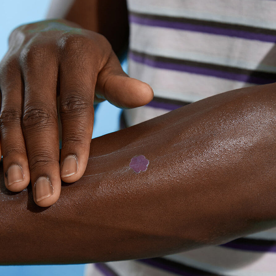 A close up of person with a BEAME UV SPF sticker on their arm.