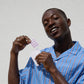 Man in a blue striped shirt holding BEAME UV SPF stickers against a light gray background.